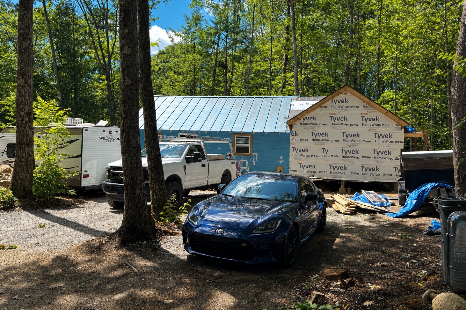 Canterbury cabin with Tyvek-wrapped addition and trucks on the job site