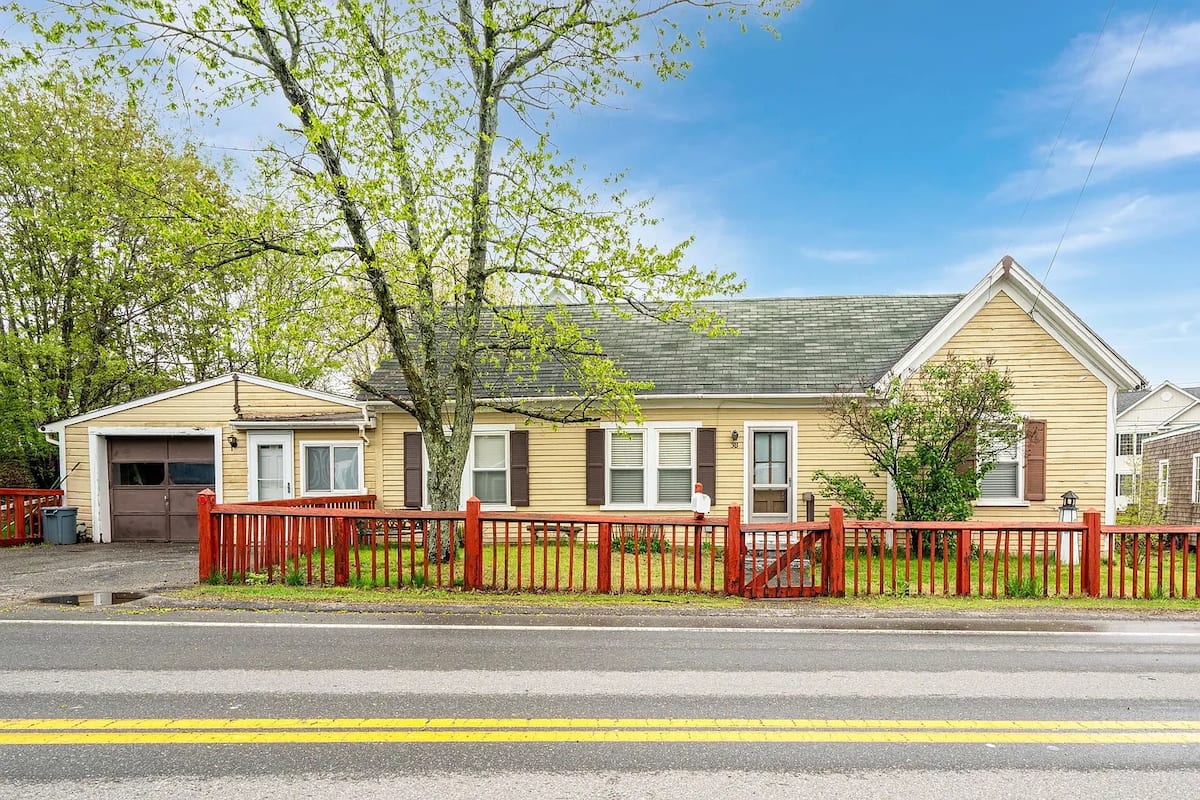 Yellow cottage exterior with red picket fence